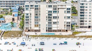 Un hôtel à étages, doté d’une piscine et d’un espace de plage aménagé avec des parasols.