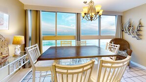 Un espace repas comprenant une grande table et des chaises, un lustre et une vue sur l’océan.