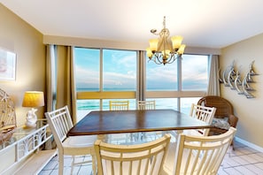 A dining area with a large table and chairs, a chandelier, and a view of the ocean. - Beachfront retreat with outdoor pool, gulf views, & W/D - perfect for long stays (Gulf Shores)