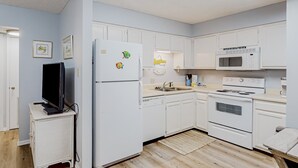Una cocina moderna con armarios blancos, microondas, horno y refrigerador.