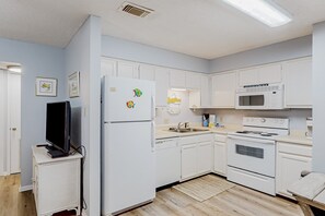 Une cuisine moderne avec des meubles blancs, un four à micro-ondes, un four traditionnel et un réfrigérateur.