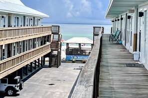 Une jetée en bois qui mène à un hôtel en bord de mer, offrant une vue sur l’océan.