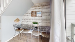 A dining area with a rustic wall, a table with chairs, and a small plant centerpiece. - Renovated condo by the beach with pool access & private balconies (Gulf Shores)