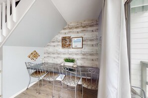 A dining area with a rustic wall, a table with chairs, and a small plant centerpiece. - Renovated condo by the beach with pool access & private balconies (Gulf Shores)