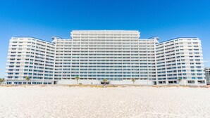 Een groot, meerijlaags hotel met een symmetrische gevel, gelegen aan een zandstrand.