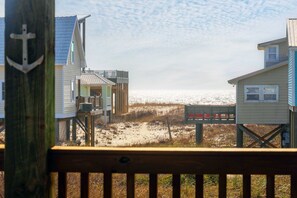 A beachfront property with multiple levels, a wooden deck, and a view of the beach and ocean. - Pristine beach home with gulf view, covered patio, and AC (Gulf Shores)