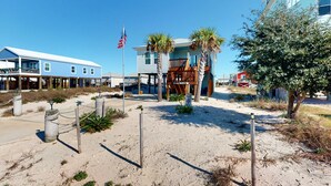Una propiedad frente a la playa con terraza de madera, una bandera y una zona arenosa.