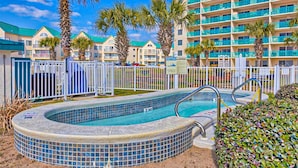 Ein Hotel mit Pool, Palmen und einem mehrstöckigen Gebäude mit Balkonen.