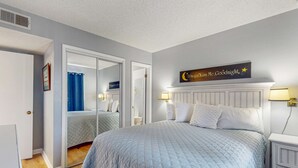 Un dormitorio con una cama grande, un espejo, una mesita de noche y un letrero en la pared.
