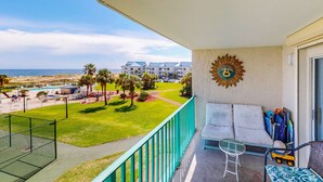 Un balcon donnant sur une piscine, une pelouse et un bâtiment situé au loin.