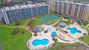 Un hôtel comprenant plusieurs étages, des piscines extérieures et un court de tennis.