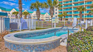 Un hôtel doté d’une piscine, de palmiers et d’un immeuble à plusieurs étages avec des balcons.