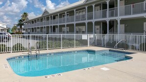 Un hôtel doté d’une piscine, d’un espace clos et d’un immeuble à plusieurs étages avec des balcons.