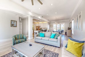 Ein geräumiges Wohnzimmer mit einer Couch, einem Couchtisch und einem gemusterten Sessel.
