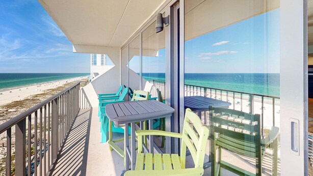 A balcony with a table and chairs, overlooking a beach and ocean. - Gulf front condo with stunning Gulf views, outdoor pool & beach access (Gulf Shores)