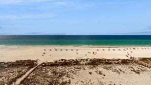 A beach with a wooden walkway leading to the shore, a sandy beach, and a clear blue sky. - Gulf front condo with stunning Gulf views, outdoor pool & beach access (Gulf Shores)