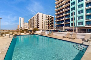 A swimming pool with lounge chairs, a lifeguard stand, and a view of high-rise buildings. - Gulf front condo with stunning Gulf views, outdoor pool & beach access (Gulf Shores)