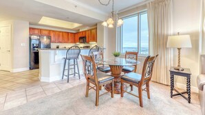 A spacious kitchen with wooden cabinets, a central island, and a dining area with a round table and chairs. - Corner condo with Gulf lagoon views, beach access & pools lazy river (Gulf Shores)