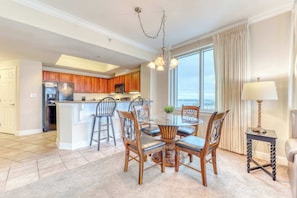A spacious kitchen with wooden cabinets, a central island, and a dining area with a round table and chairs. - Corner condo with Gulf lagoon views, beach access & pools lazy river (Gulf Shores)