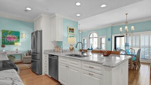 A modern kitchen with white cabinetry, a marble countertop, and a built-in dishwasher. - 3BR/3BA Dune Ridge Condo with Elevator, Pool & Ocean Views (Wrightsville Beach)