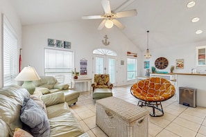 A spacious living room with a ceiling fan, a sofa, a chair, and a small table. - Dog-Friendly Gulfside Home with Private w/d, ac, WiFi, Balcony, Deck (Gulf Shores)
