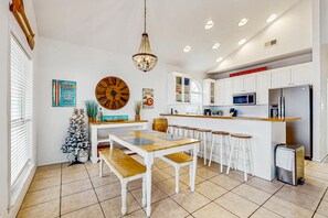 A kitchen with white cabinets, a wooden island with stools, a chandelier, and a small Christmas tree. - Dog-Friendly Gulfside Home with Private w/d, ac, WiFi, Balcony, Deck (Gulf Shores)
