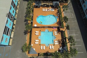 An aerial view of a hotel with a swimming pool, sun loungers, and palm trees. - Waterfront condo with a furnished balcony, peek-a-boo Gulf views, & shared pools (Gulf Shores)