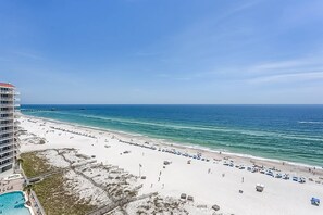 A beach view with a hotel, a swimming pool, and a pier in the background. - Gulf-Front Condo w Beach Access, WiFi, Balcony & Shared Pools, Hot Tubs & Gym (Gulf Shores)