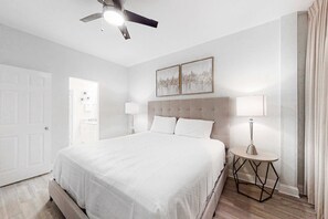 A bedroom with a bed, two bedside lamps, a ceiling fan, and a door. - Gulf-Front Condo w Beach Access, WiFi, Balcony & Shared Pools, Hot Tubs & Gym (Gulf Shores)
