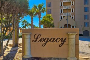 A building with a sign that reads 'Legacy.' - Gulf-Front Condo w/ Balcony, Gorgeous View, WiFi, AC & Shared Outdoor Pool (Gulf Shores)