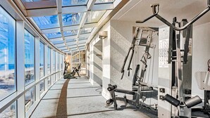 Uma academia com equipamentos de exercício, janelas amplas e um claraboia.