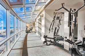 Ein Fitnessstudio mit Trainingsgeräten, großen Fenstern und einem Oberlicht.