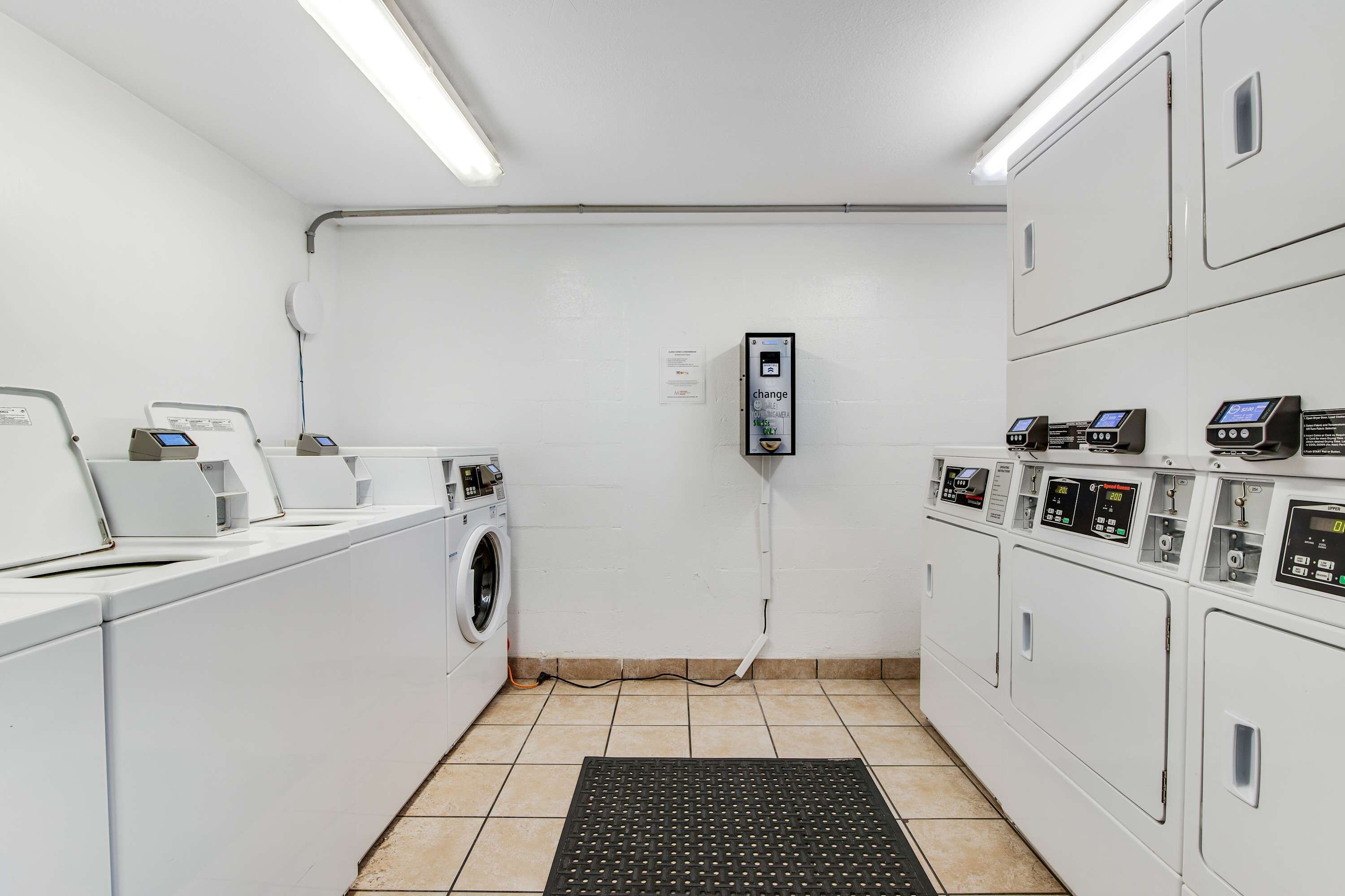 A laundry facility with multiple washing machines, dryers, and a control panel.