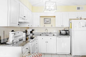 A kitchen with white cabinets, a coffee maker, a microwave, and a refrigerator. - Corner Condo w Amazing Gulf-Front Views, Balcony & Shared Pools Hot Tubs Gym (Gulf Shores)
