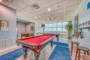 A pool room with two pool tables, a bar area, and a view of the ocean. - Incredible oceanfront condo with balcony, AC, pool, gym & hot tub (Gulf Shores)