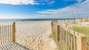 En sandstrand med trästaket och en klar himmel.