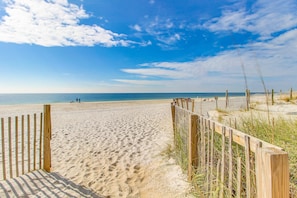 A sandy beach with wooden fences and a clear sky. - Incredible oceanfront condo with balcony, AC, pool, gym & hot tub (Gulf Shores)