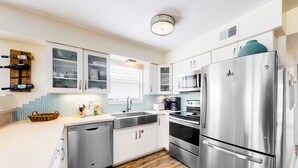 A modern kitchen with stainless steel appliances, white cabinetry, and a wooden floor. - Beachfront home with furnished waterfront deck, balcony, & central AC (Gulf Shores)