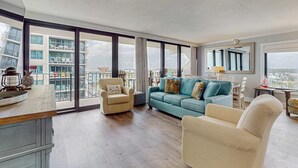 Ein geräumiges Wohnzimmer mit großem Fenster, einer Couch, einem Sessel und einem Essbereich.
