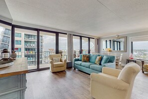 Ein geräumiges Wohnzimmer mit großem Fenster, einer Couch, einem Sessel und einem Essbereich.
