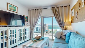 Un salon avec un téléviseur, des meubles blancs, un canapé et une vue sur la ville.