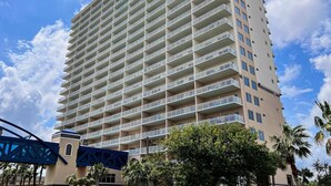 Un grand hôtel doté de nombreux balcons, un pont piétonnier bleu et des palmiers.