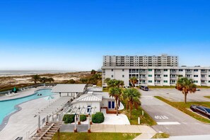 Et hotel med flere etager, en swimmingpool, et overdækket område og udsigt til stranden.