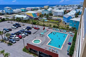 Ein Resort mit Pool, Parkplatz und farbenfrohen Gebäuden.
