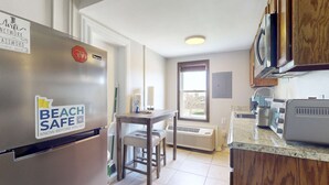 Uma cozinha com geladeira, mesa e janela.