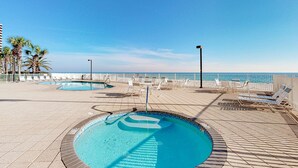 A pool area with lounge chairs and a view of the ocean. - Oceanfront condo with pool, elevator, well-equipped kitchen, balcony, & W/D (Gulf Shores)