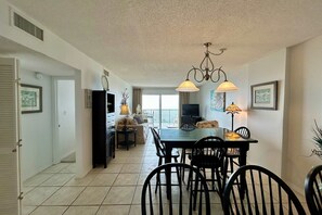 A dining area with a table, chairs, and pendant lights. - 6th-floor beach-view condo with outdoor pool, tennis court, sauna, hot tub, gym (Gulf Shores)