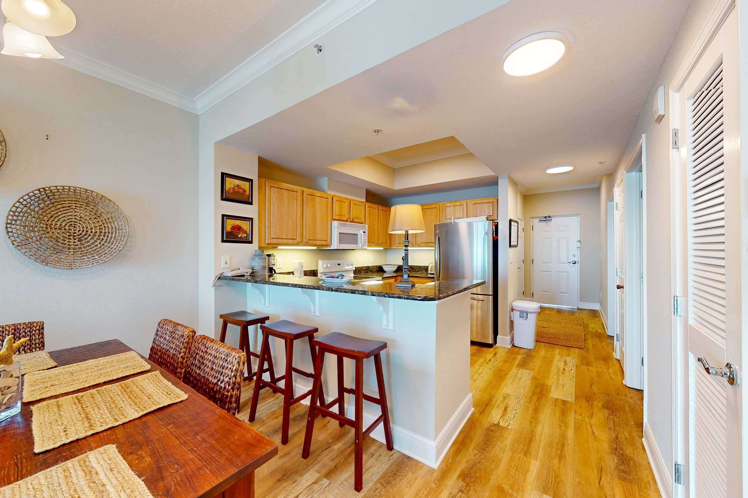 A kitchen with wooden cabinets, a central island, bar stools, a dining table, and a microwave.