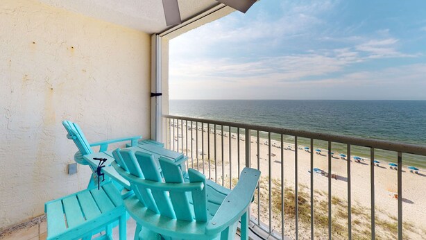 A balcony with a view of the beach and ocean, turquoise chairs, and a ceiling fan. - Inviting condo with ocean view, on-site pool, cozy balcony, washer/dryer & AC (Gulf Shores)