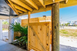Une structure en bois dotée d’un toit incliné, d’une porte en métal et d’un plancher en béton.